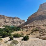 Turquoise wadi pool framed by rock canyon walls